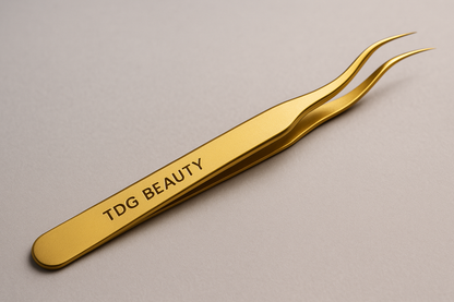 une pince de couleur or qe les techniciennes utilise pour manipulez les cils de leurs clientes avec ecrit tdg beauty dessus